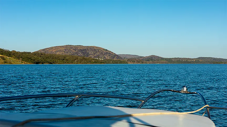 Proa de barco na represa em direção às montanhas